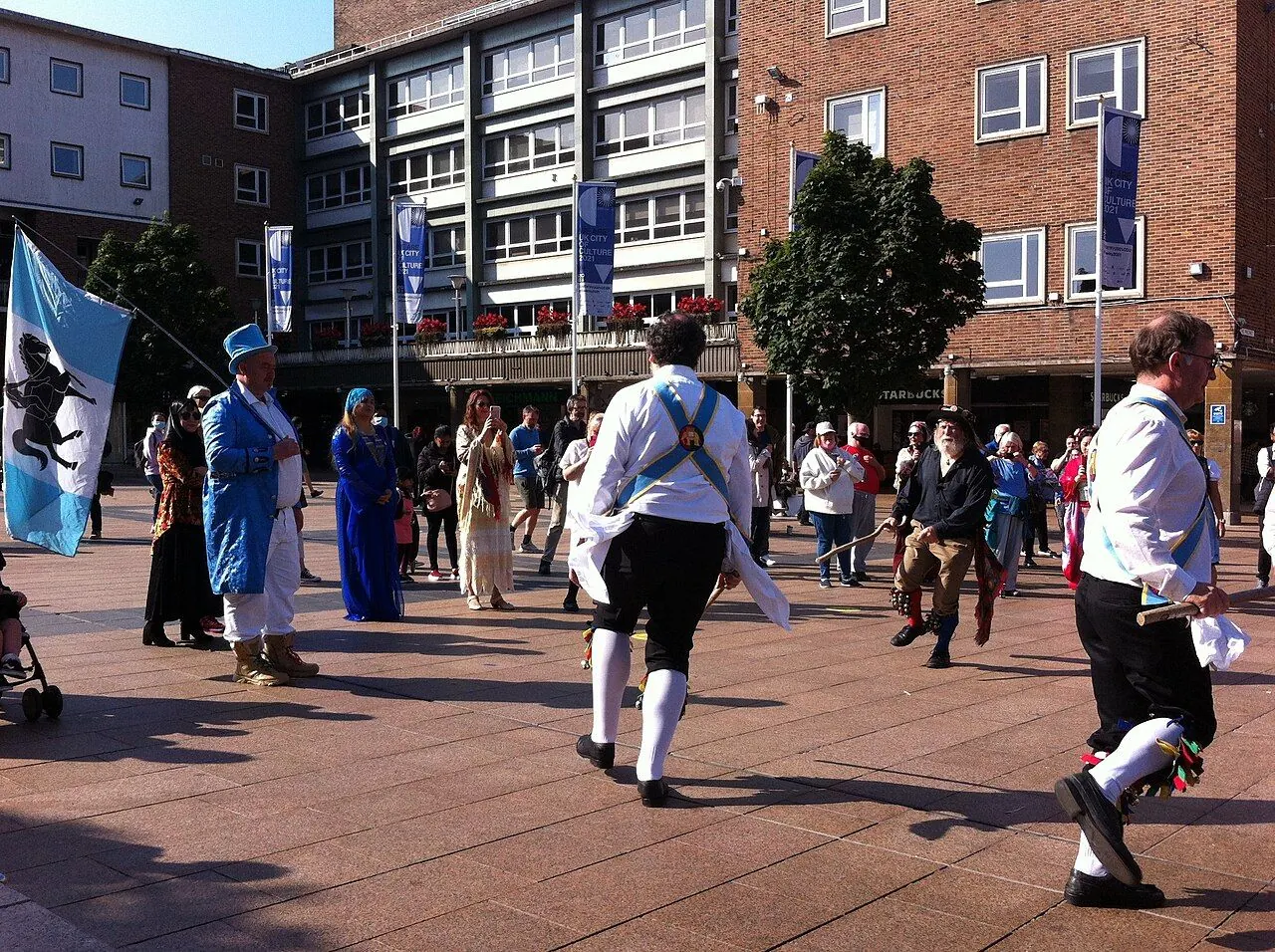 Morris dancers with bells and handkerchiefs dancing outdoors
