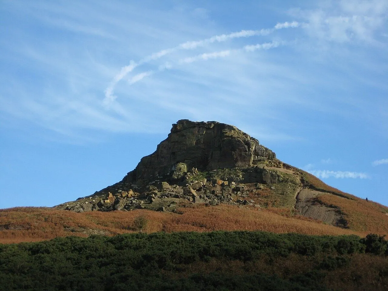 Walker on a moorland path above a heather valley